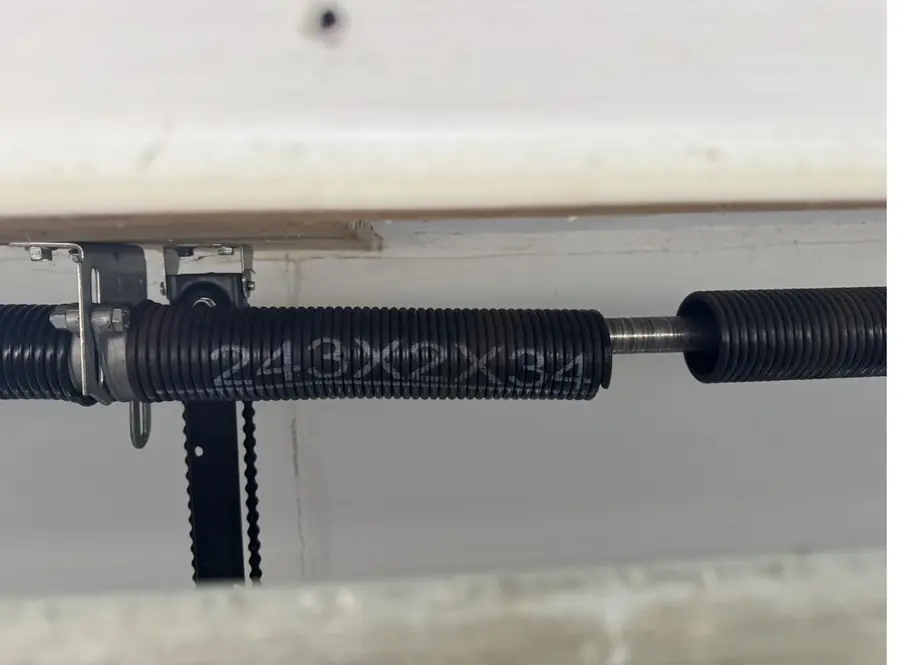New torsion spring installed on the shaft above a garage door